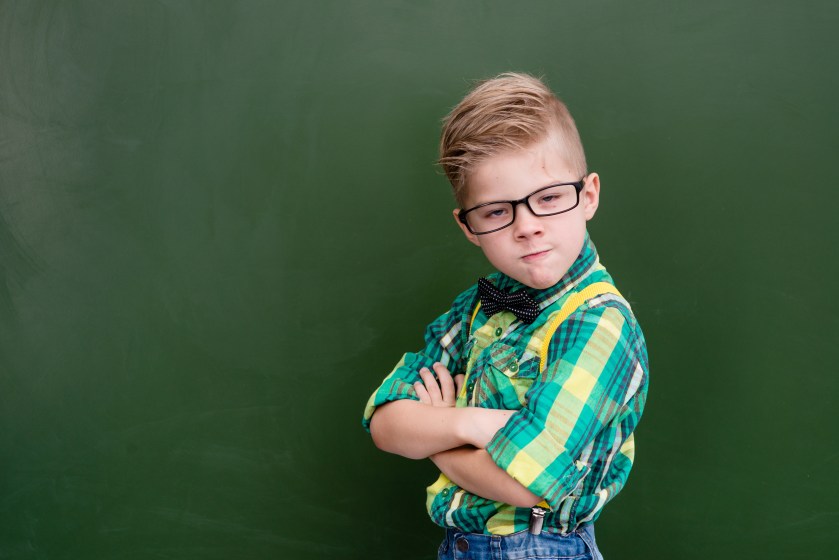 Funny angry nerd near empty green chalkboard
